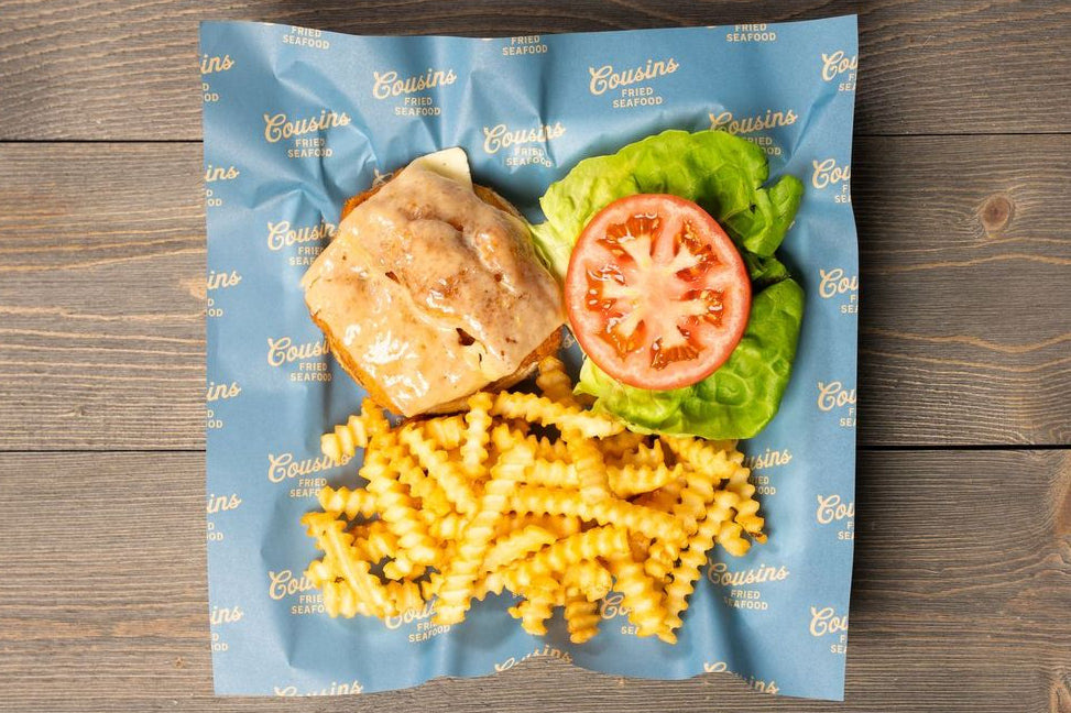 Packaged meal with pasta, sandwich, and vegetables on a wooden surface